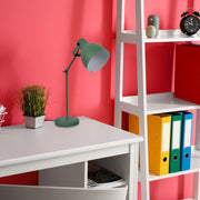 A green desk lamp illuminates a study space. The bright light showcases a modern, minimalist design.