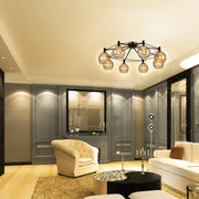 A contemporary, eight-bulb chandelier-style ceiling light fixture with spherical, amber-tinted glass shades, illuminating a stylish living room.
