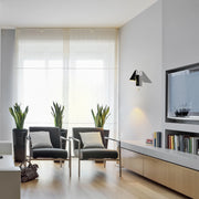 Contemporary lighting: a wall-mounted sconce provides warm accent lighting in a modern living room with natural light from large windows.