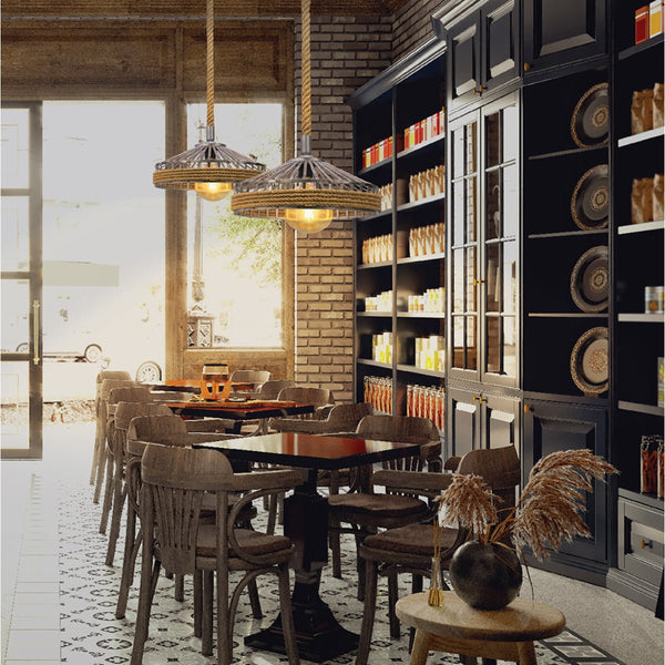 A rustic dining area with wooden chairs, dark tables, and stylish rope pendant lights, complemented by a dark wood shelving unit.
