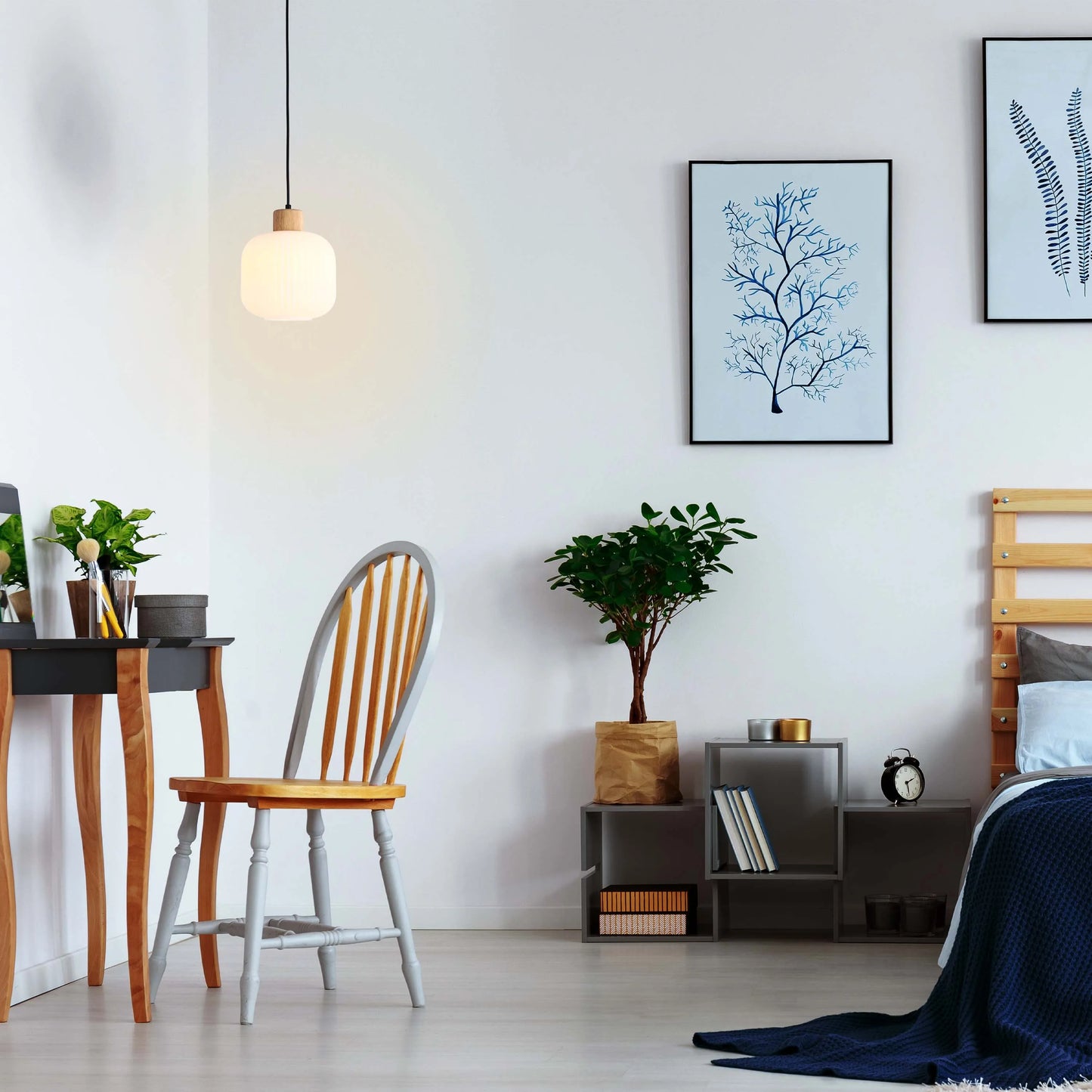 Pendant light with a rounded, matte shade, suspended by a black cord, provides soft, ambient lighting in a modern bedroom setting.