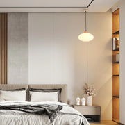A pendant light hangs above a bedroom. The warm glow highlights a sleek, minimalist design, adding a touch of cosiness to the space.