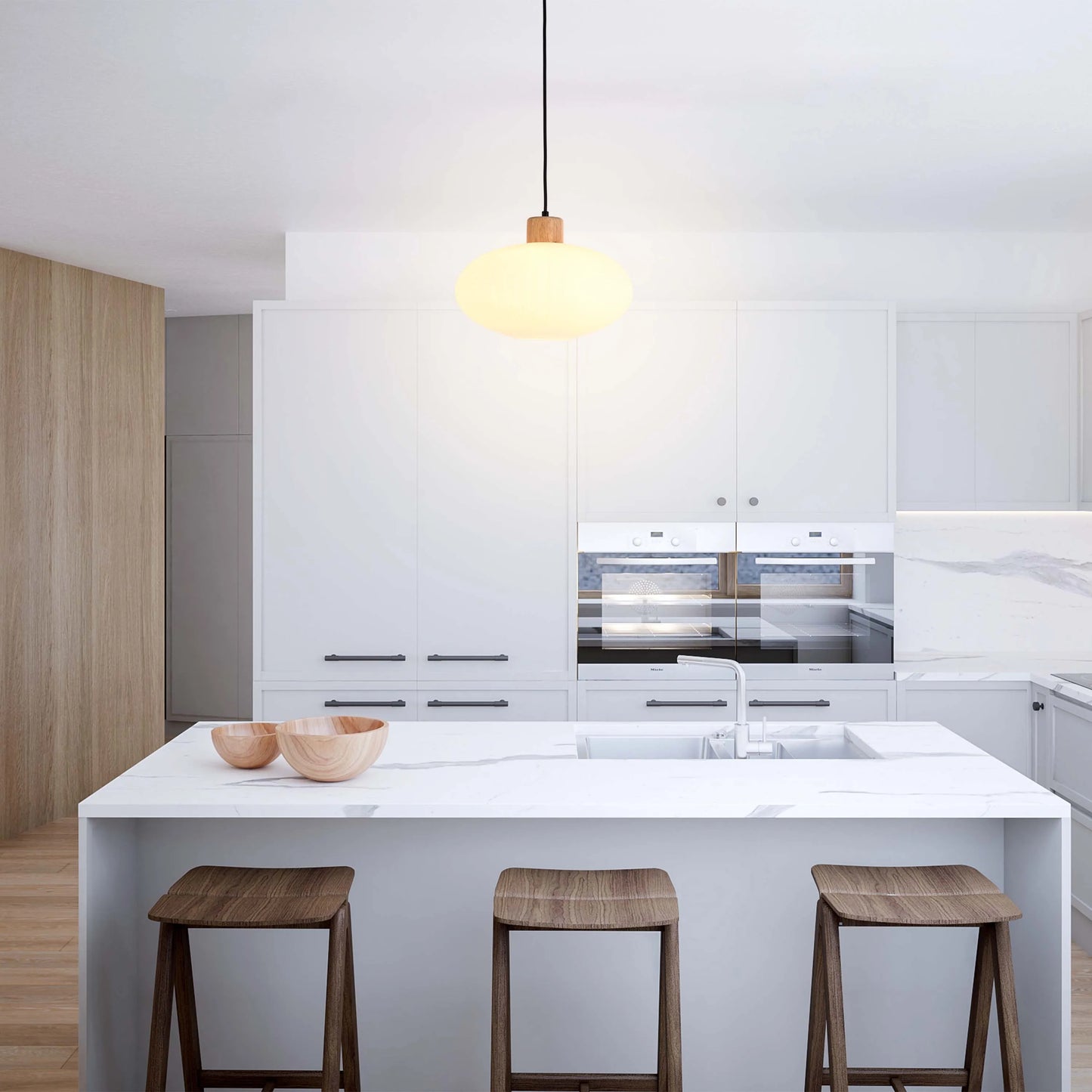 A minimalist kitchen with a pendant light, featuring a round, frosted glass shade and a wooden accent, suspended above a marble island.